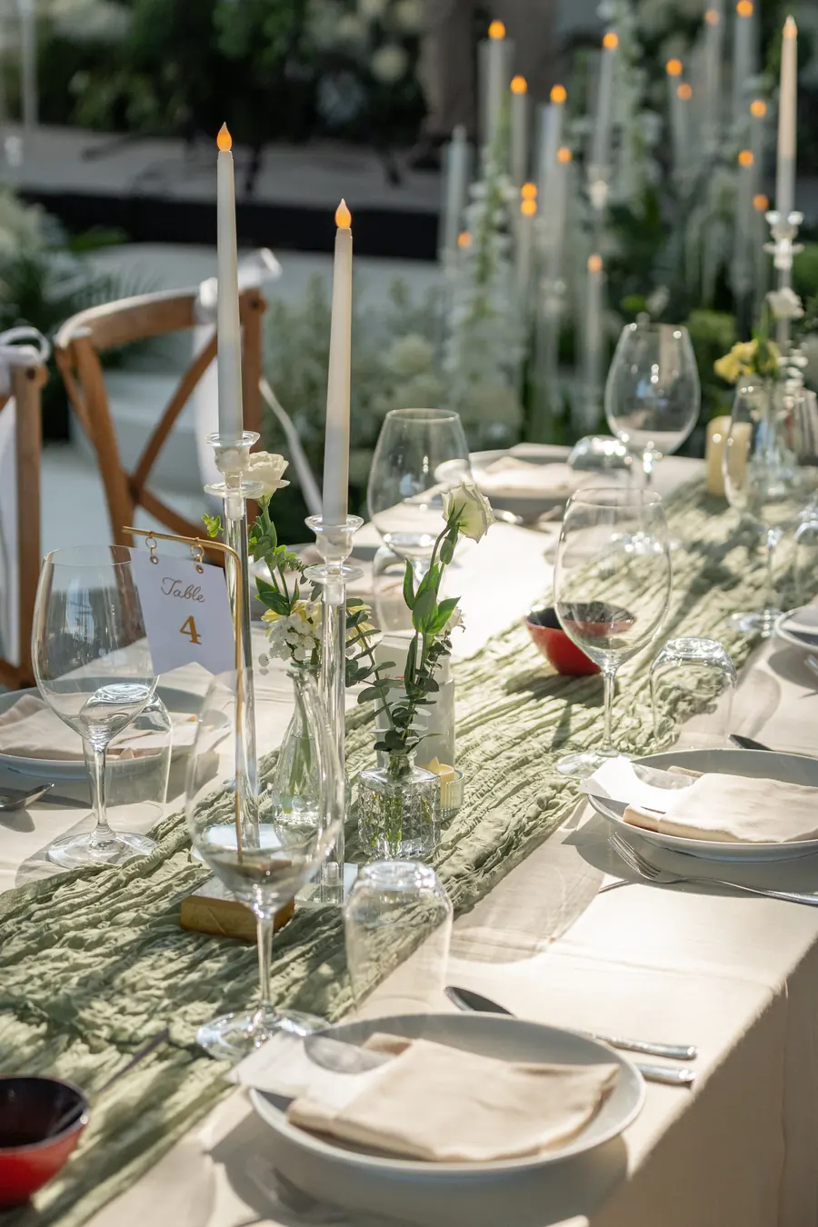 Glass candle holders and white flowers along an elegantly dressed wedding table