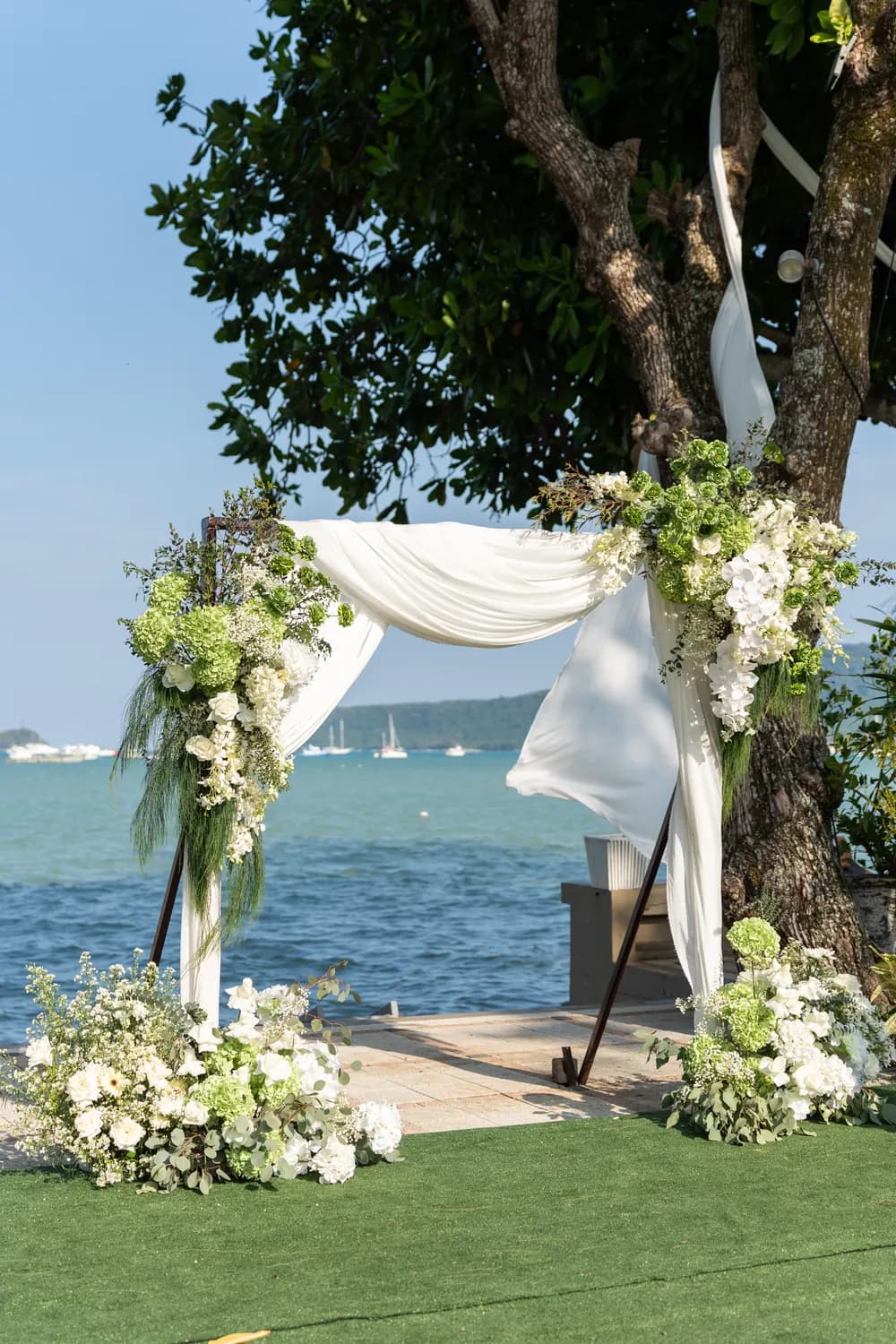 A flower-covered ceremony arch beside the sea at KEP