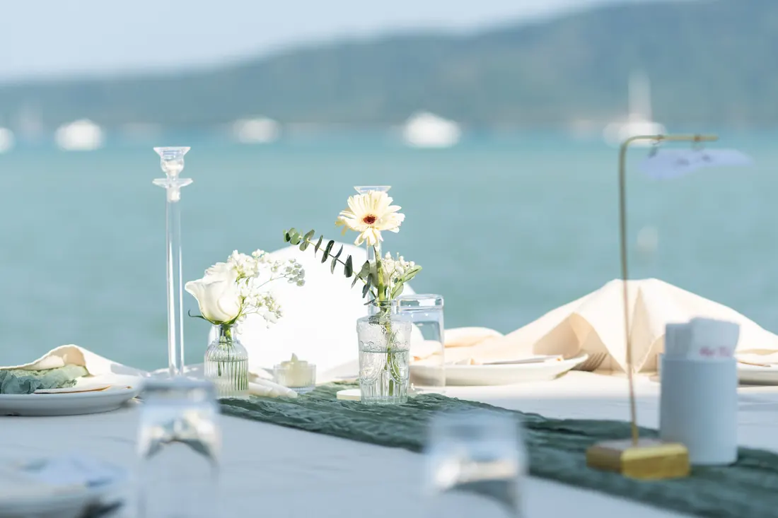 Daisies, candles and white linen at a waterfront wedding table